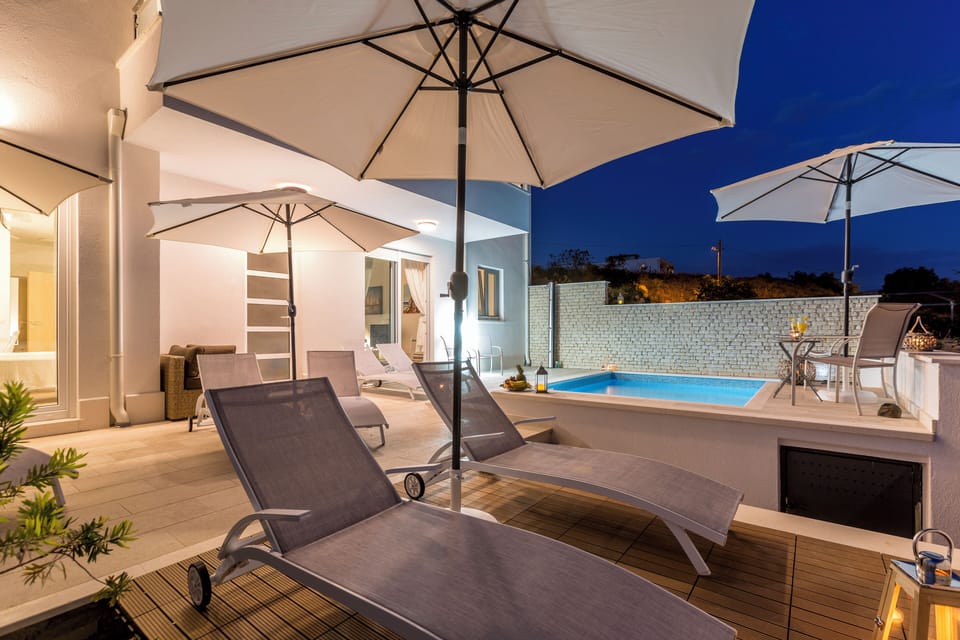 Outdoor pool with sun loungers during daytime.