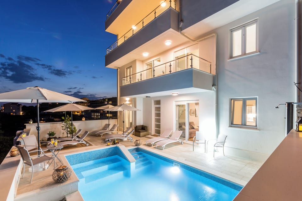 Outdoor pool with sun loungers during daytime.