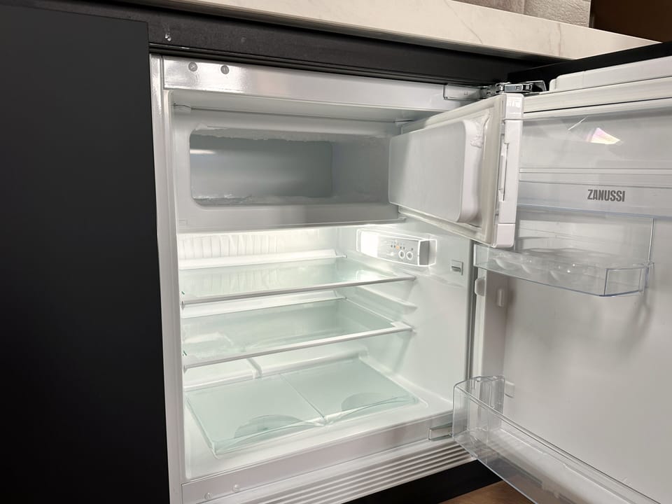 Clean compact fridge with glass shelves and freezer compartment, ideal for storing fresh food and drinks in a modern, well-equipped kitchen.