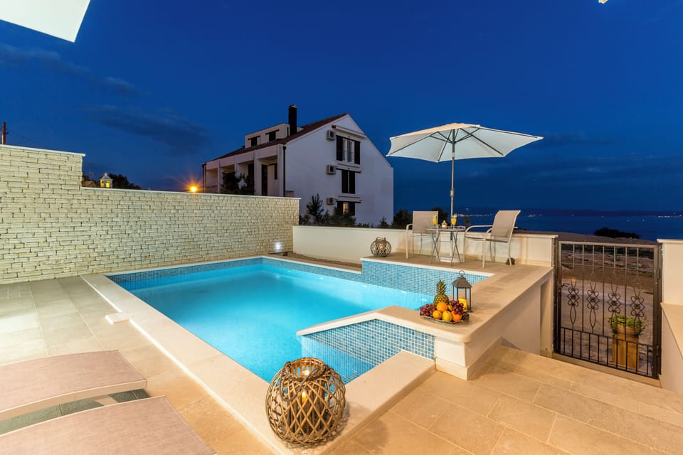 Outdoor pool with sun loungers during nighttime.