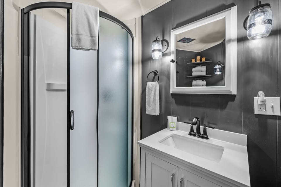 Step into your modern bathroom with sleek gray walls, rainfall shower, and white vanity—everything you need for refreshing mornings.