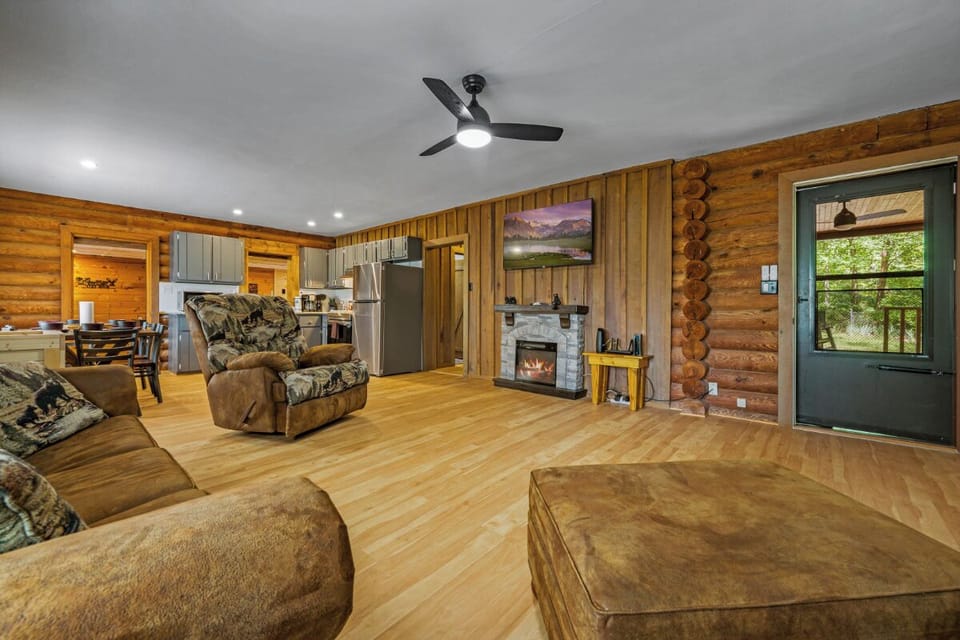 Unwind in your rustic living room where warm wood walls meet cozy furniture, perfect for relaxing by the stone fireplace after adventurous days.
