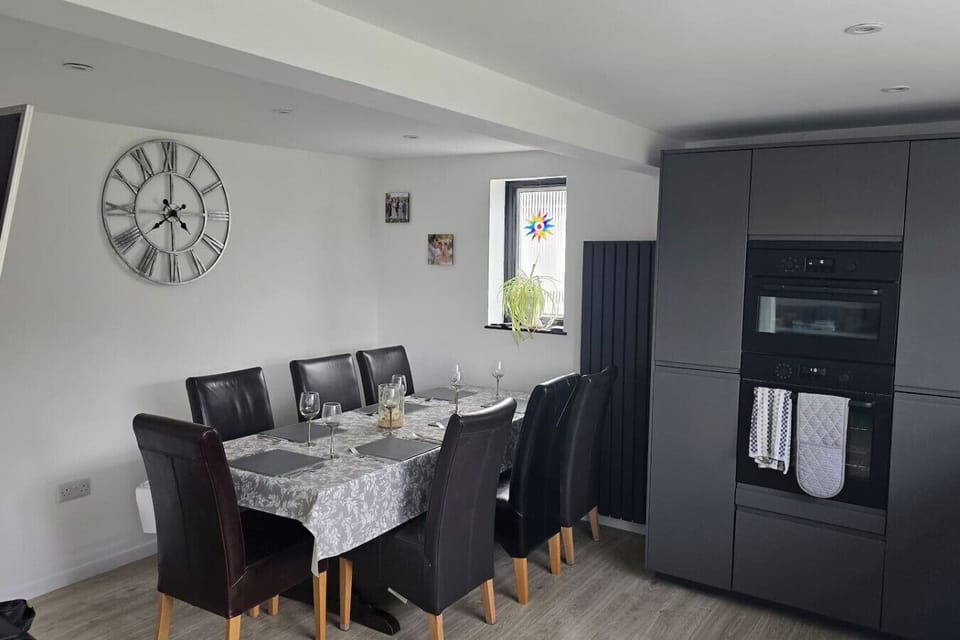 A dining table with chairs set next to grey fitted kitchen units.