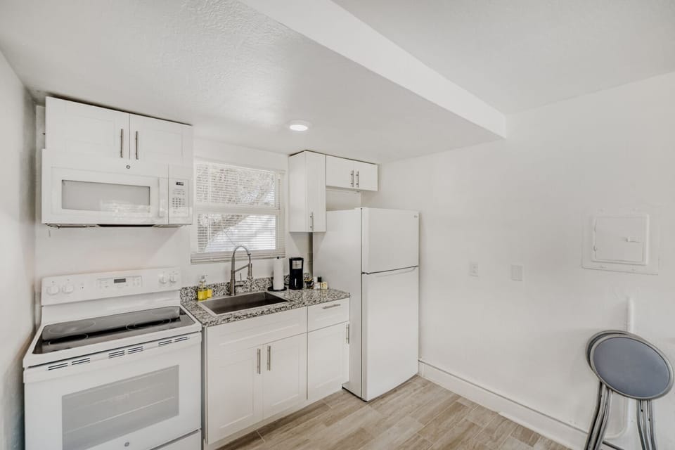 Modern kitchenette features a stovetop, full-size fridge, microwave, coffee maker, and ample cabinetry for all your culinary needs.