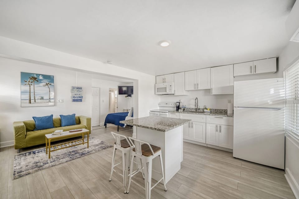 Open-plan living area with a dedicated wood-top desk and blue chair — work-from-home ready with high-speed Wi-Fi