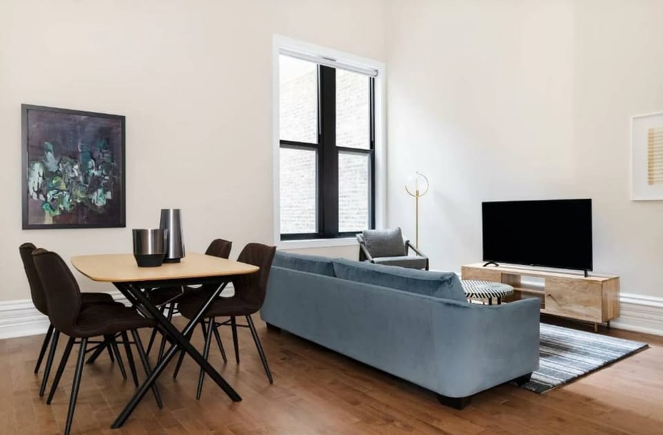 Spacious living area with sofa, smart TV, and dining table for meals or remote work