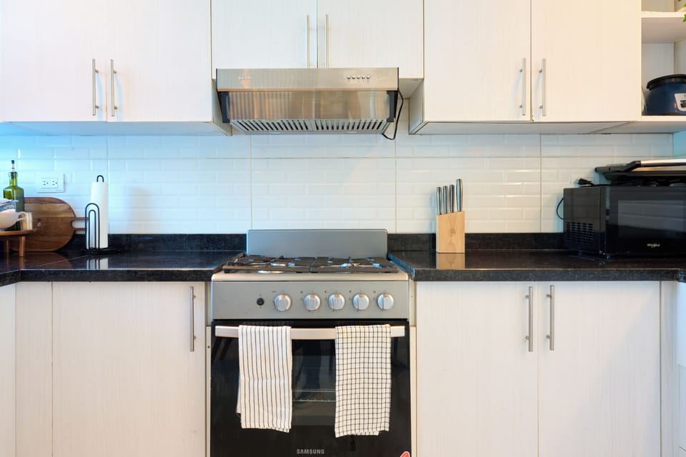 Modern fully equipped kitchen with stove, oven, range hood, and ample storage sp