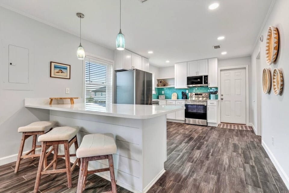 This gorgeous modern kitchen features stainless steel appliances, a spacious island with seating, and a stunning turquoise tile backsplash.