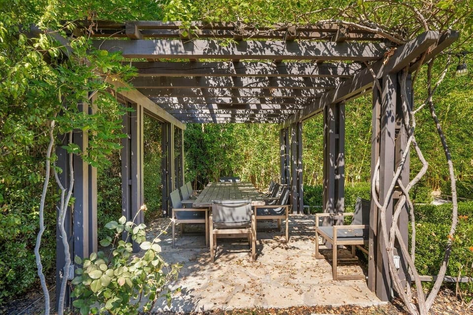 A covered patio with built-in seating, intended for outdoor dining or lounging under shade.