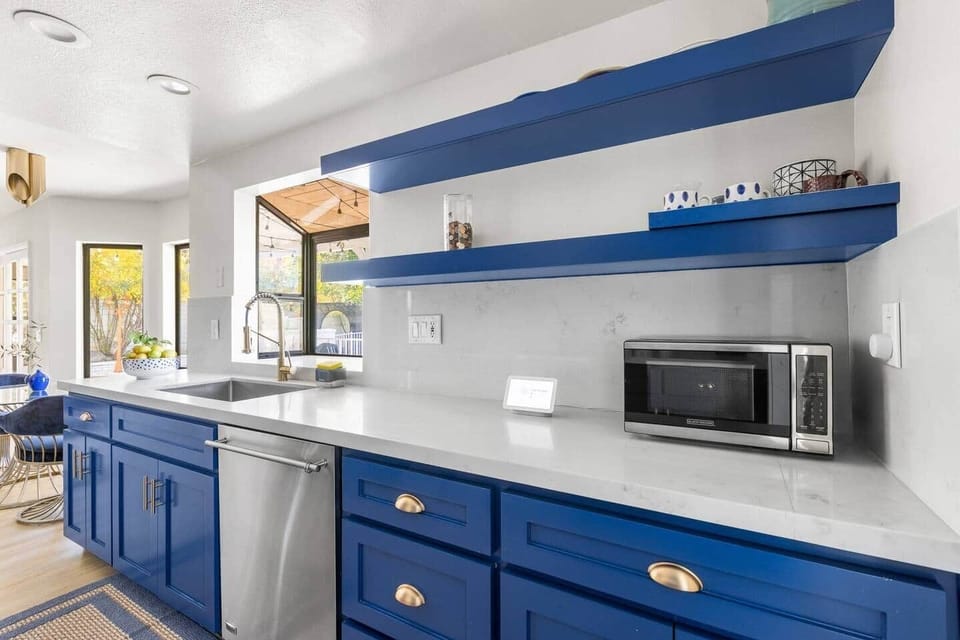 Sleek blue cabinets provide massive storage, while open shelving offers a spot for spices.