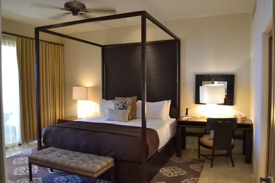 Unwind in a sleek canopy bed with warm glow.