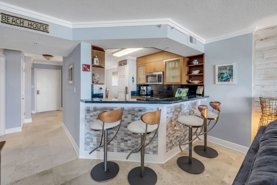Barstools at the kitchen counter provide bonus seating, perfect for casual dining, morning coffee, or gathering after a beach day
