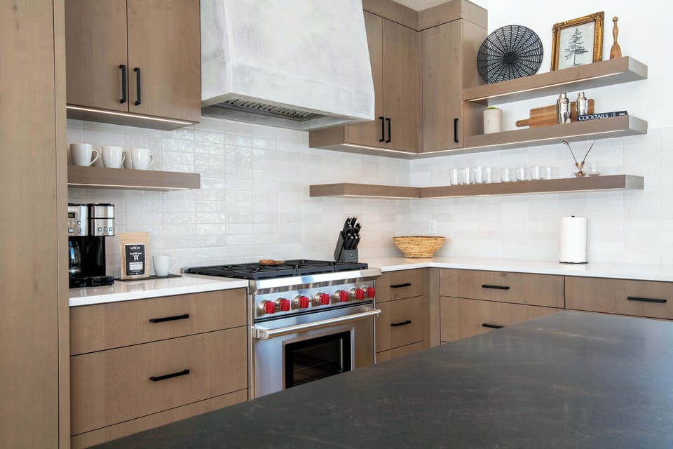 Professional-grade range with custom hood and tile backsplash — Antelope Abode's kitchen is built for serious cooks and the big group meals that follow.