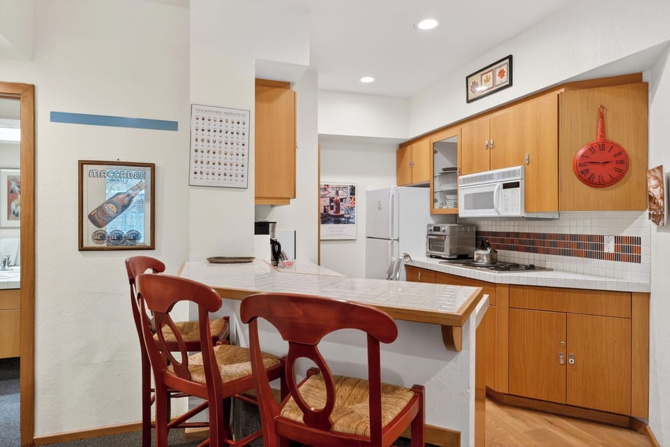 Compact, fully equipped kitchen with breakfast bar seating — perfect for morning coffee or easy après-ski meals at home.
