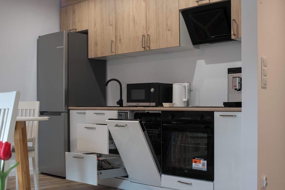 An open integrated dishwasher in the kitchen, showing the modern appliances available for guest use. The kitchen is fully integrated, combining the aesthetics of wood with modern household technology.