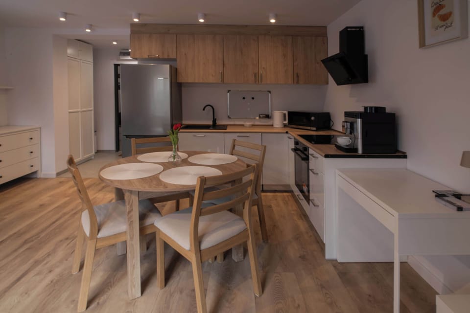 The dining area includes a wooden table with four matching chairs, situated conveniently between the kitchen and the rest of the living space.
