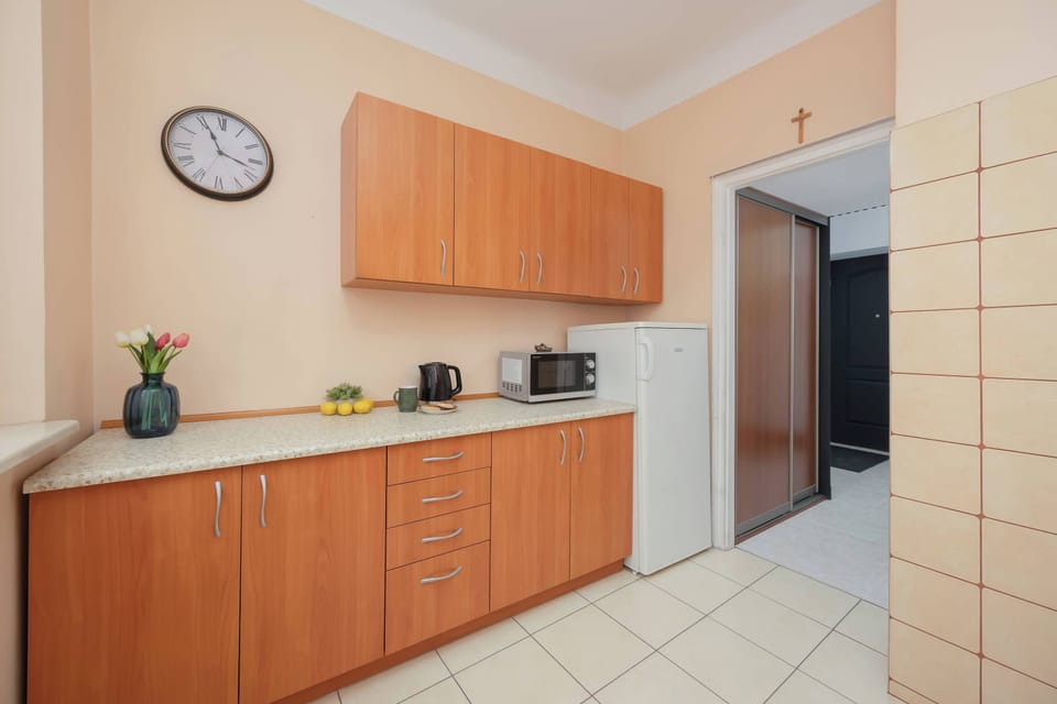 A compact kitchen with wooden cabinets and light-colored tiled walls. The layout appears practical and efficient.