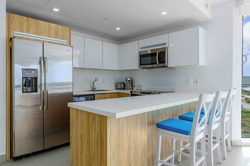 Your fully equipped kitchen features sleek white countertops, stainless steel appliances, and a breakfast bar where you can sip morning coffee.