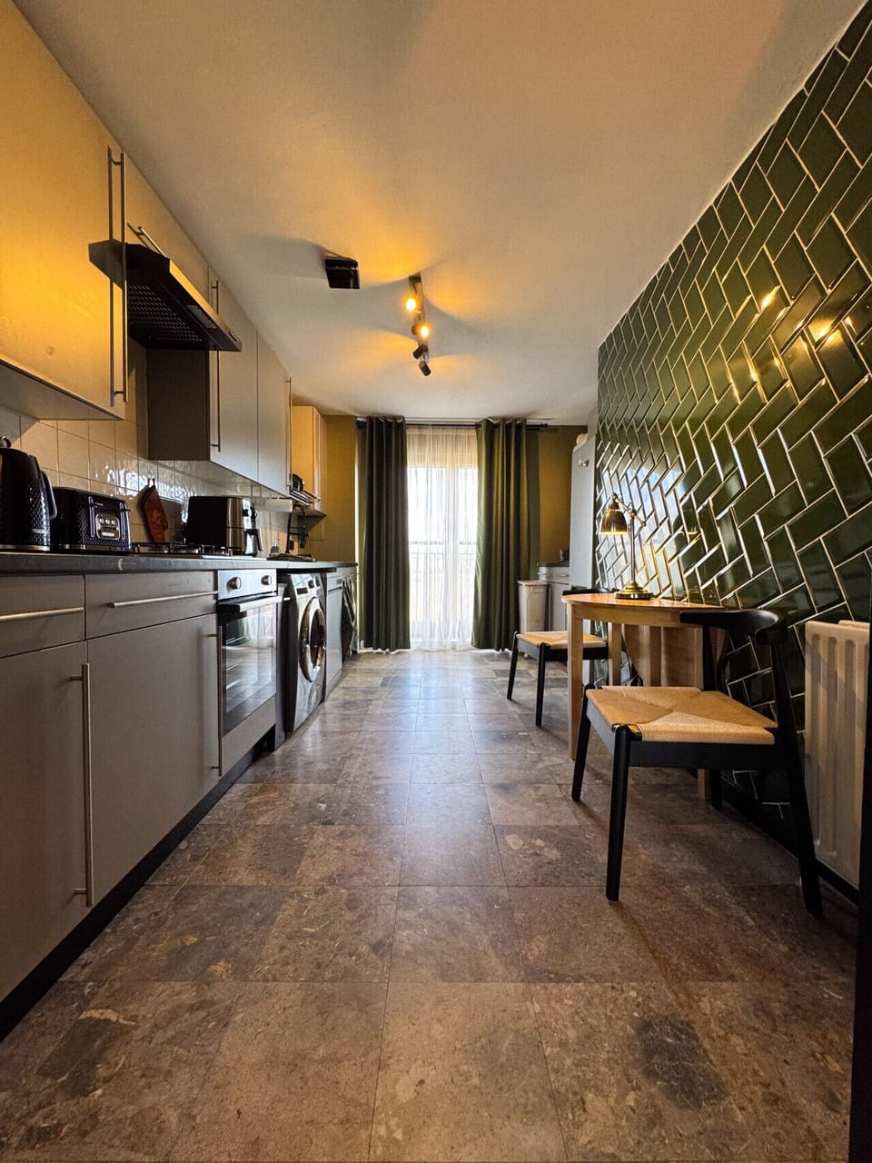 ully equipped modern kitchen with beautiful green tile feature wall.