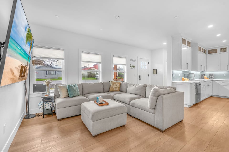 Sink into this plush sectional sofa and enjoy your open-concept living space with modern kitchen and bright natural light streaming through oversized windows.