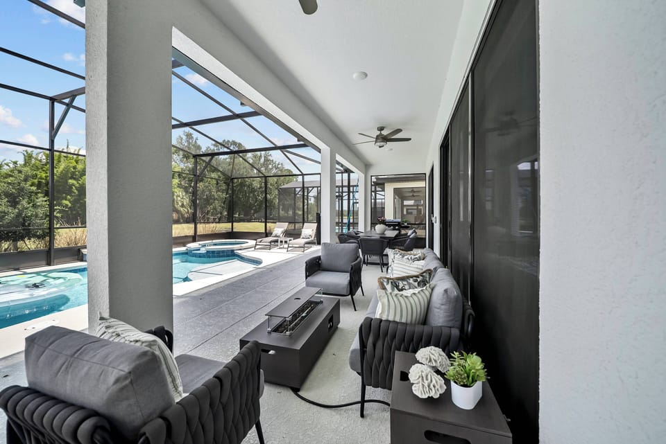 Relax in our stylish lounge with sleek black wicker seating and cozy cushions, perfect for unwinding. Enjoy natural light and views of the inviting pool just steps away in our spacious, screen-enclosed area.