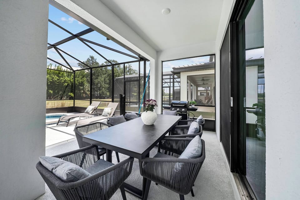 Step onto this stylish patio, featuring a sleek dining table and comfy chairs for al fresco meals. The large screened enclosure provides a clear view of the sparkling pool, perfect for relaxing sunny days.