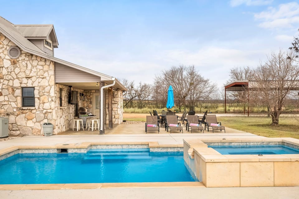 Step outside to your private backyard oasis featuring a refreshing outdoor pool, a hot tub with sun loungers and seating.