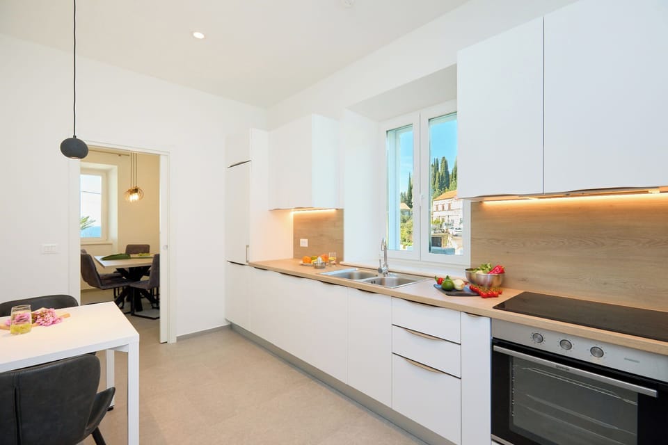 Prepare meals in a sleek, modern kitchen with warm lighting and a scenic view, fully equipped for all your culinary needs.