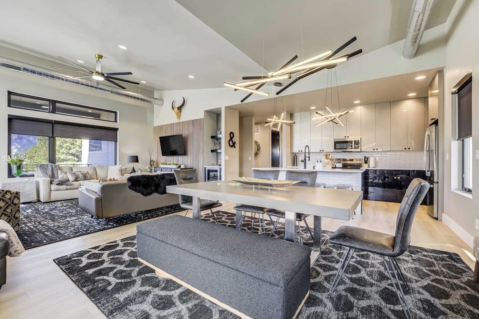 The open-concept layout seamlessly connects the dining area to the kitchen and living room. High ceilings and exposed ductwork provide an industrial-modern edge, while large windows ensure the entire space is bathed in light.