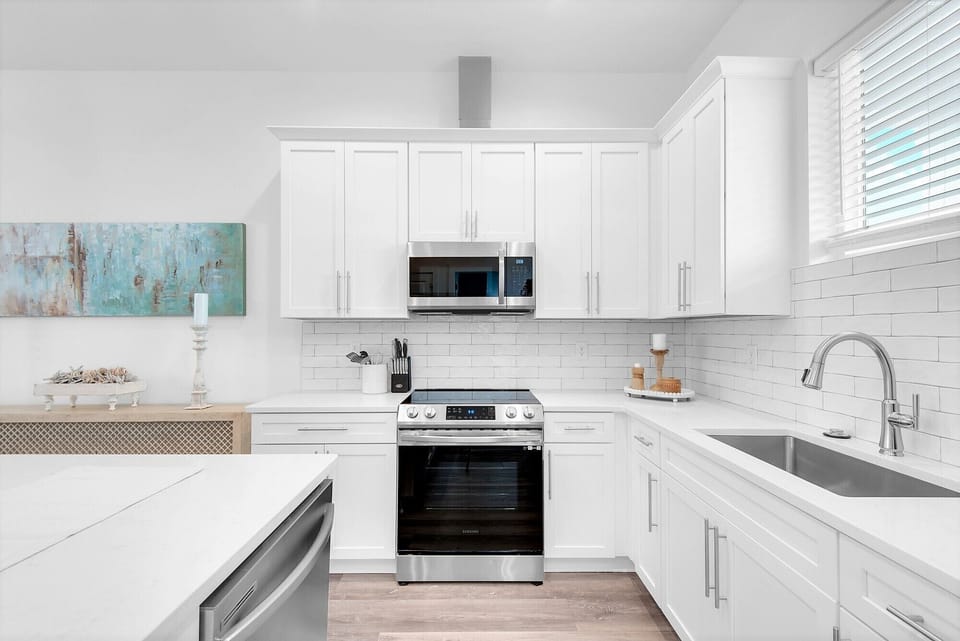 Tile backsplash, stainless appliances, and farm sink gleam in Bliss's kitchen!