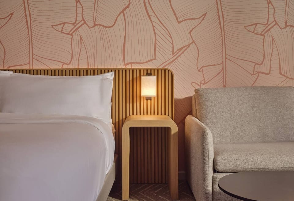 Unwind in crisp bedding beside a cozy lounge corner.