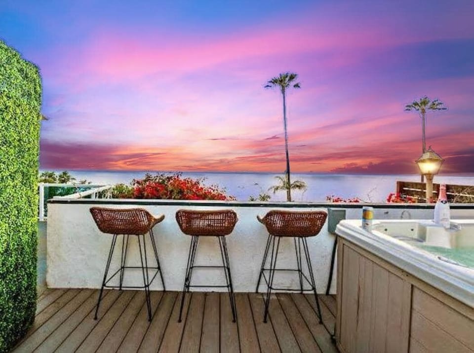 A sunset scene that takes your breath away—8-person hot tub, ocean views, and the perfect setting of wicker and metal chairs facing the horizon. With vibrant bougainvillea and proud palm trees framing the moment, it’s pure paradise at dusk.