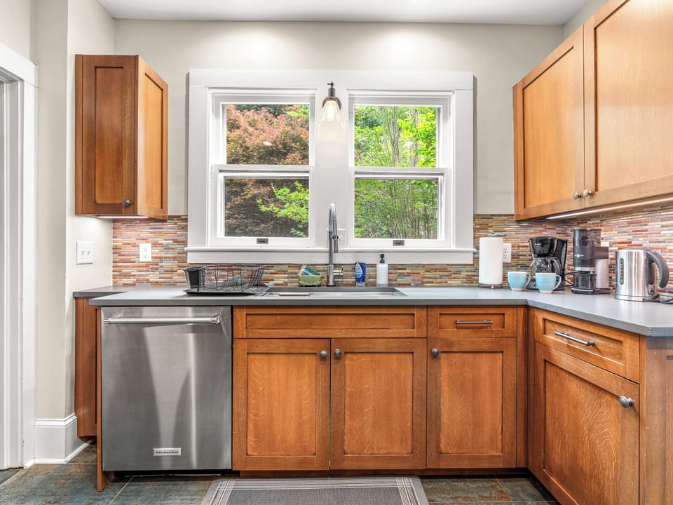 Bright updated kitchen with garden views, stainless appliances, and warm wood cabinetry