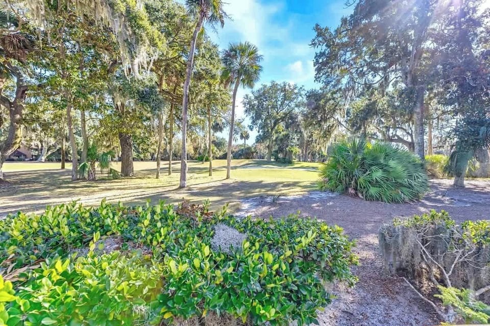 Peaceful landscaped grounds feature mature oak trees draped with Spanish moss and tropical palms creating natural shade throughout the property.