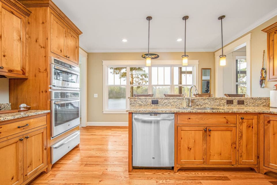 Bright and fully equipped kitchen with granite counters, modern appliances, and bar seating.