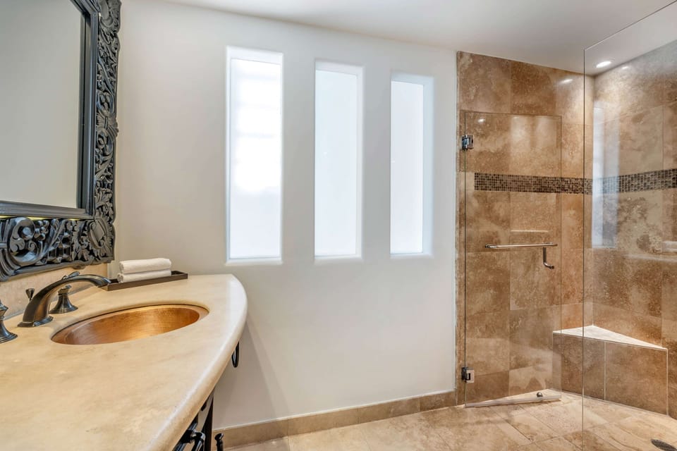 Refresh in a sleek, glass shower with warm stone finishes.
