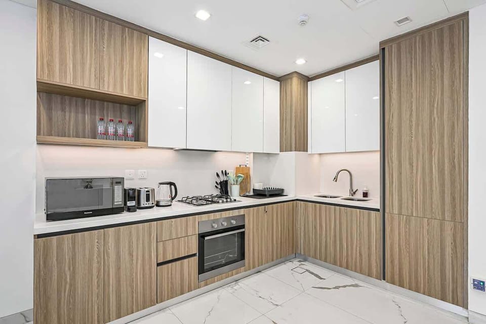 The sleek, modern kitchen is fully equipped with everything you need - including a gas stovetop, oven, microwave, kettle, toaster, and Nespresso machine. Ample cabinet space, cookware to prepare meals at home and full-size fridge
