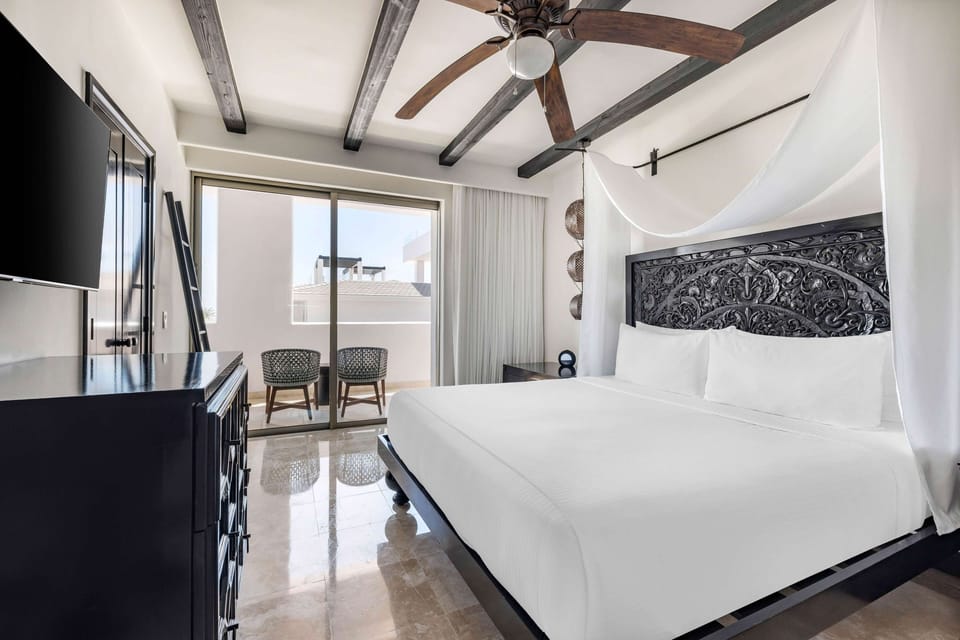 Drift off beneath carved headboard and soft canopy linens.