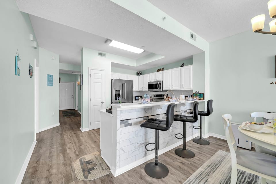Your spacious kitchen welcomes you with gleaming white cabinets, stainless steel appliances, and a marble-topped island where you'll gather for meals.