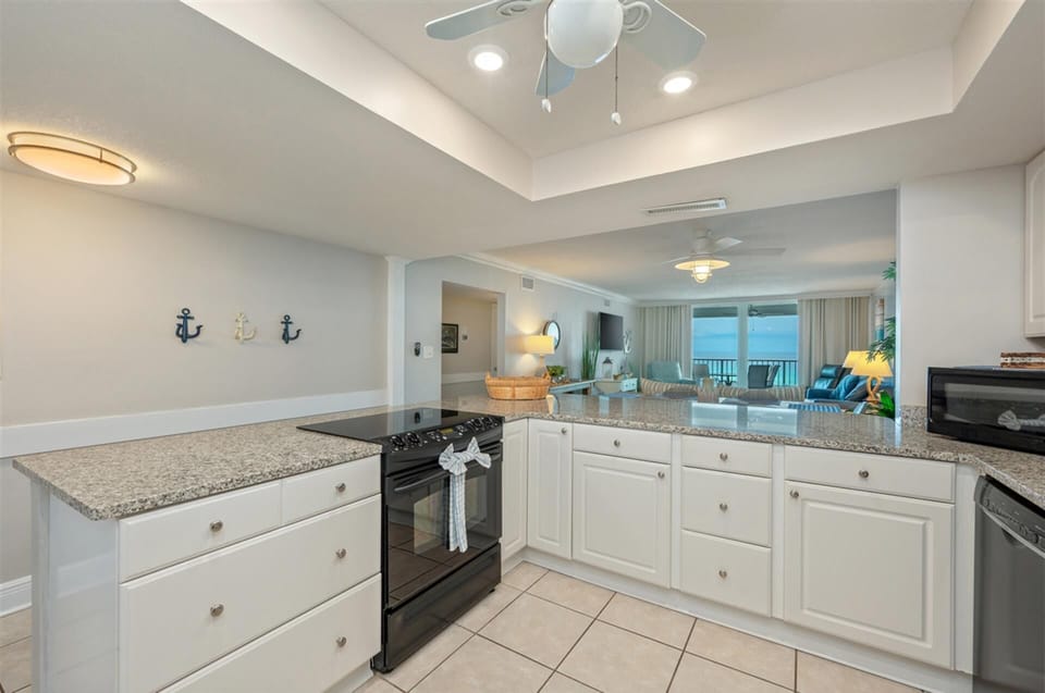 Your gourmet kitchen features granite countertops, full appliances, and nautical touches, opening to a living space with stunning sea views.