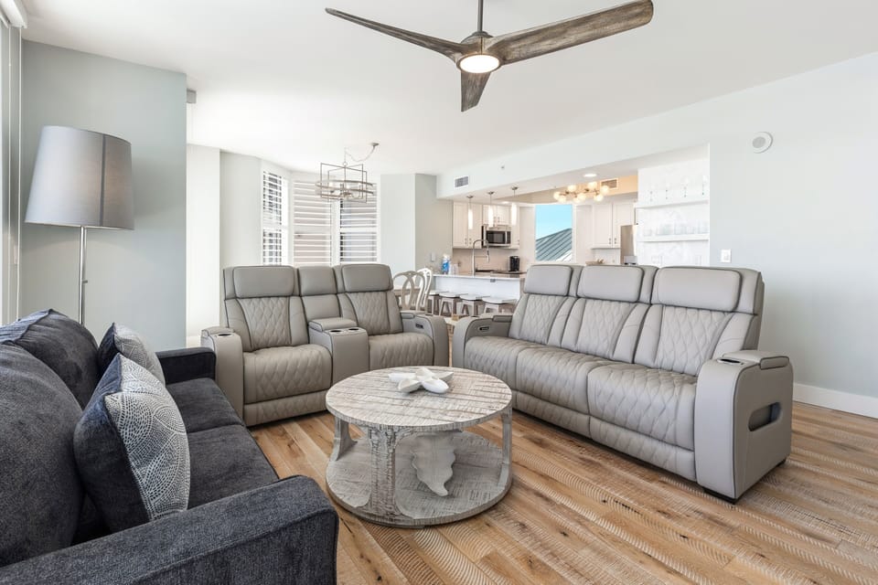 Unwind in your spacious living room featuring plush leather recliners, a cozy sectional sofa, and elegant coastal décor throughout this bright, airy space.