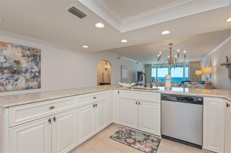 Your elegant white kitchen features granite countertops and stainless appliances, with stunning ocean views through the open living space.