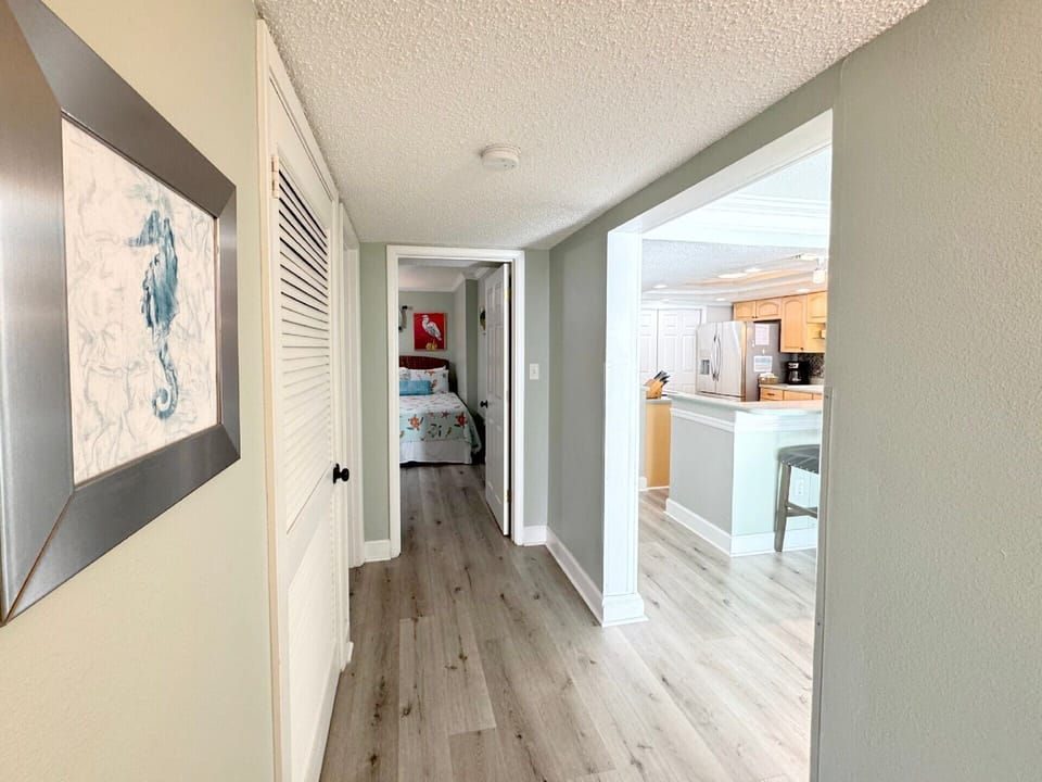 You'll love the open flow connecting your private hallway to the bright, modern kitchen with coastal artwork guiding your way.