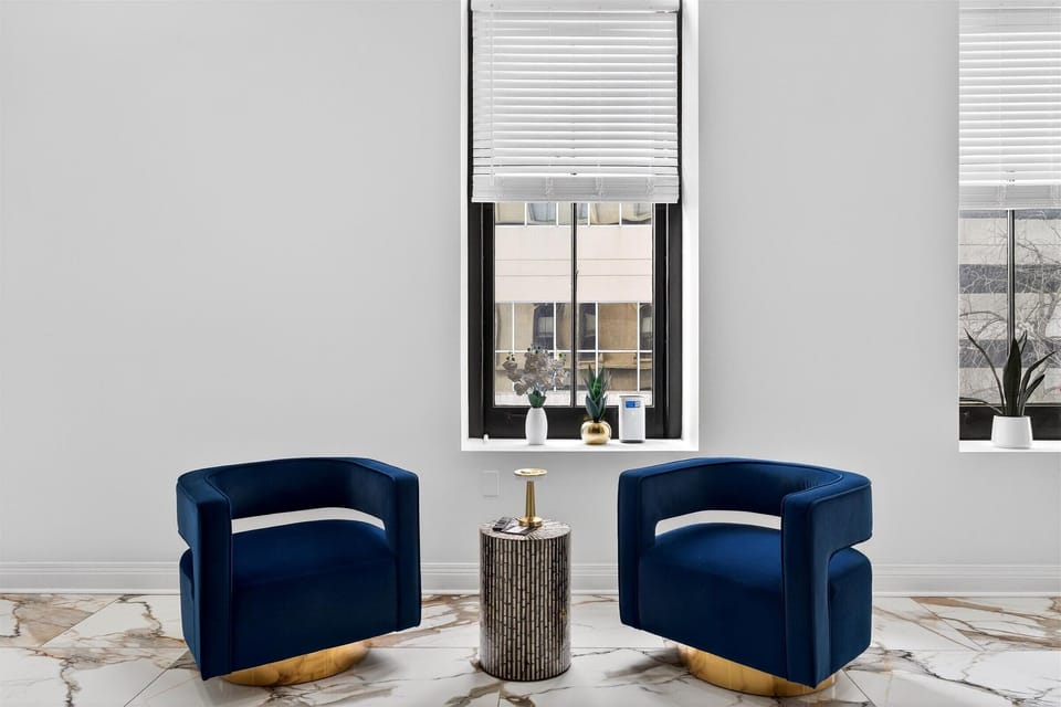 A closer look at the plush texture of the blue chairs and the modern gold accents. It is a perfect spot to read or people watch.