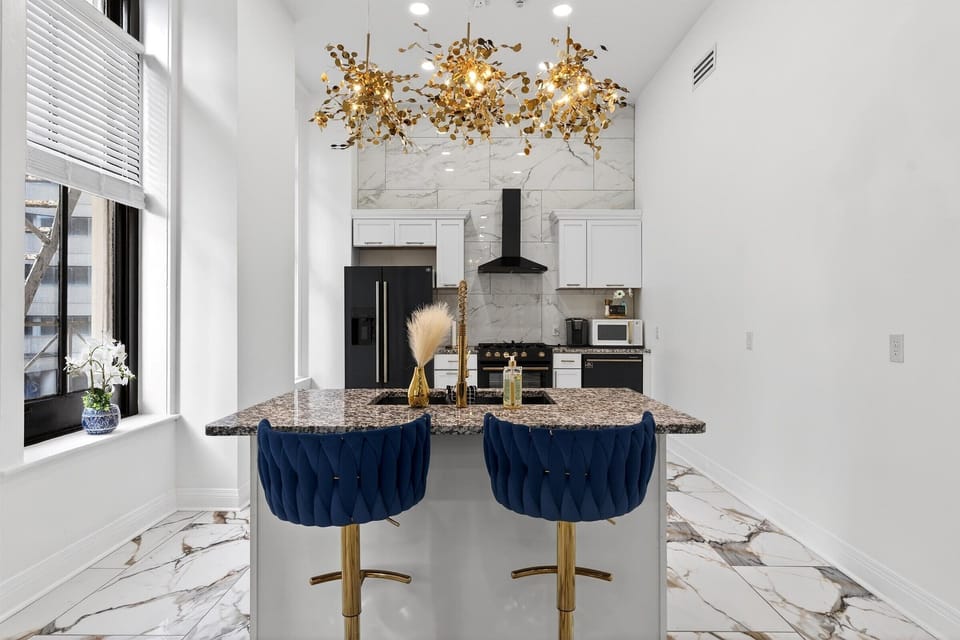 The kitchen features a spectacular gold Sputnik chandelier above the granite island. Pull up a blue velvet bar stool and enjoy the luxe vibe.