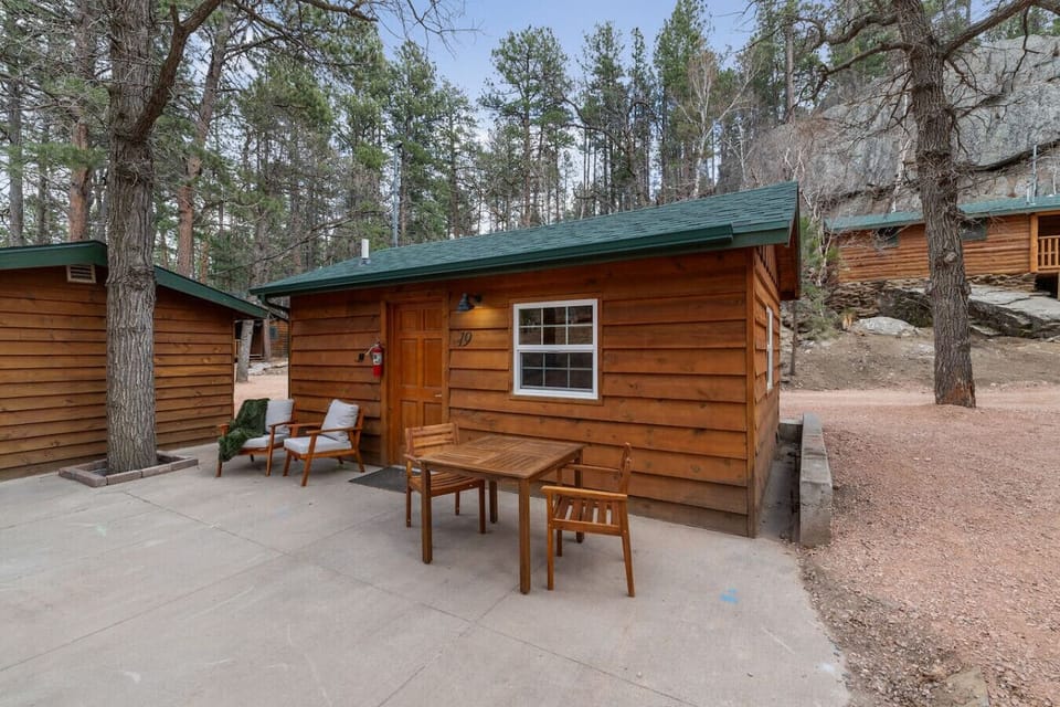 Enjoy your own private cabin with outdoor seating, perfect for relaxing in a peaceful forest setting.