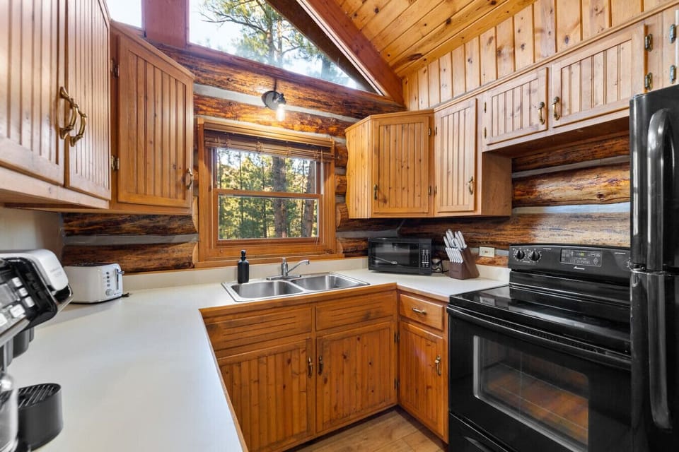 Rustic, fully equipped kitchen with full-size fridge, stove and microwave. Cook meals at your Hillside Country Cabin getaway.