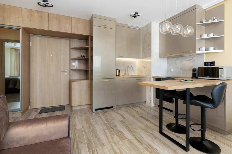 From this angle, the hallway leads into the kitchen area, showing the functional layout of the apartment’s entrance. Built-in storage cabinets in a light wood finish offer ample space for guest belongings.