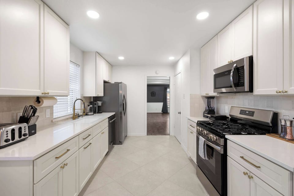 Cook up a feast in this sleek, chef-ready kitchen featuring bright white cabinetry, expansive quartz countertops, and a full suite of modern appliances.