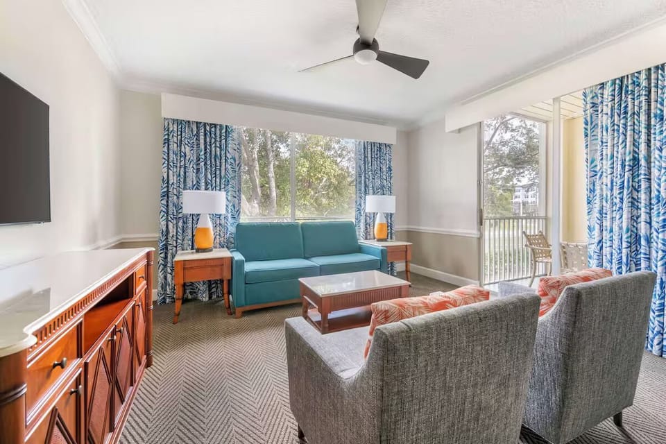 Gather for cozy chats beside sunlit windows and balcony doors.